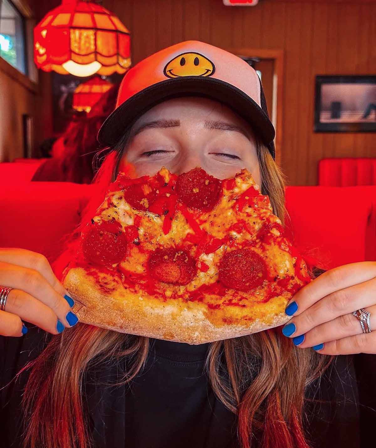 Female Holding a Half Eaten Pizza Slice - Sauced