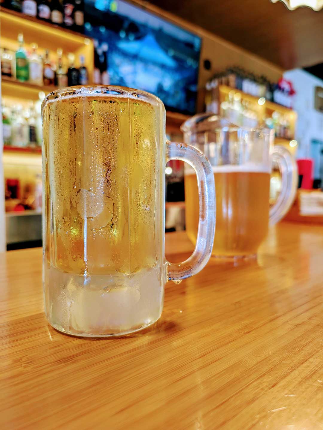 Beer in a Clear Mug with a Beer Pitcher in the Background at the Sauced Bar